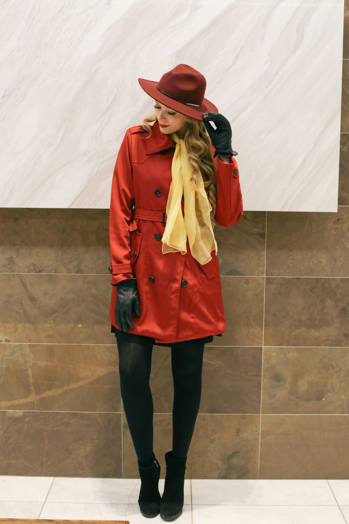 Carmen Sandiego DIY Halloween Costume: wearing a red trench coat, red fedora and yellow scarf.